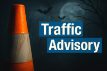 Traffic cone with text "Traffic Advisory" against a dark, eerie background with bats and moon.