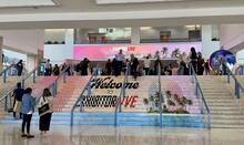 Staircase with cling that reads welcome to Exhibitor Live with many attendees walking and an LED banner that reads Exhibitor Live Tampa Florida.