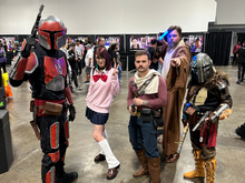 Group of cosplayers at TBCC 2024 in costume at a convention hall.