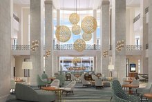 Photo of the new Tampa Marriott Water Street Lobby shows updated furniture with a classic modern design. Large orb-lights hang from the tall ceilings and couches, arm chairs, and tables fill the lobby.  Photo courtesy of Tampa Marriott Water Street.
