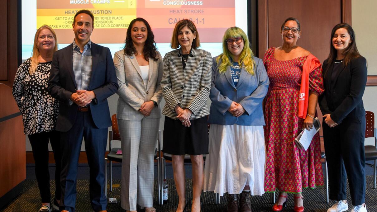 Seven people standing in front of a heat safety event presentation slide.