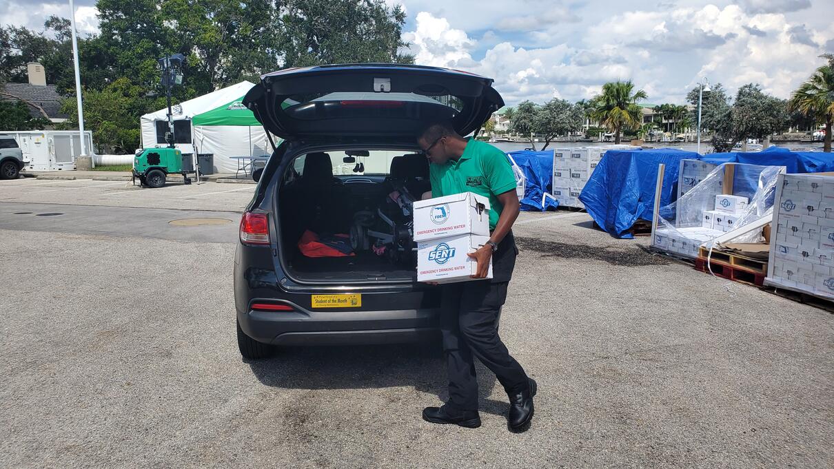 Man unloading boxes from a car in a parking lot, October 2023.