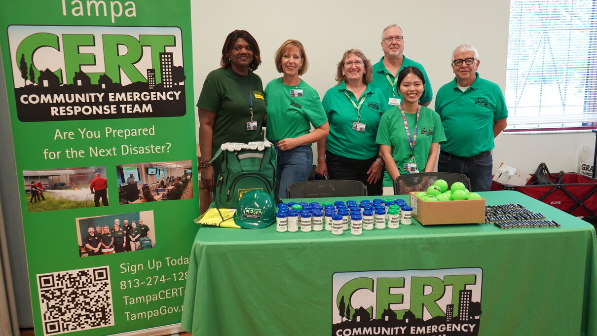 Tampa Community Emergency Response Team booth with six smiling volunteers in green shirts.