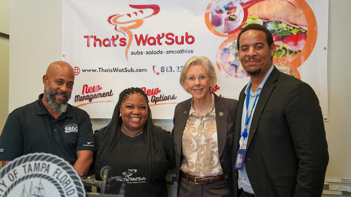 Group of five people smiling in front of a "That's WatSub" banner.
