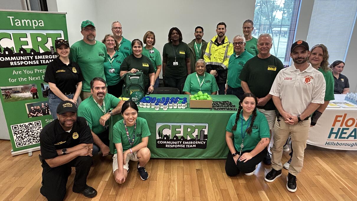 Group of people in green shirts at CERT event, displayed informational booths.