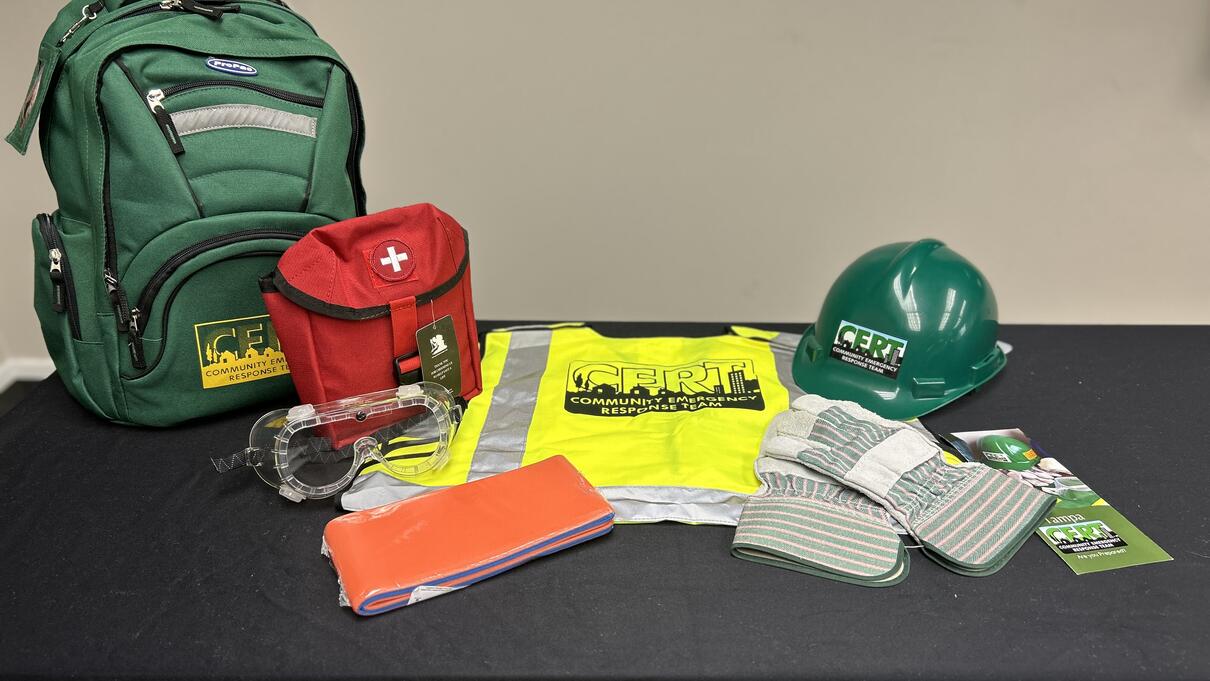 Emergency preparedness kit with backpack, helmet, vest, and first aid supplies.