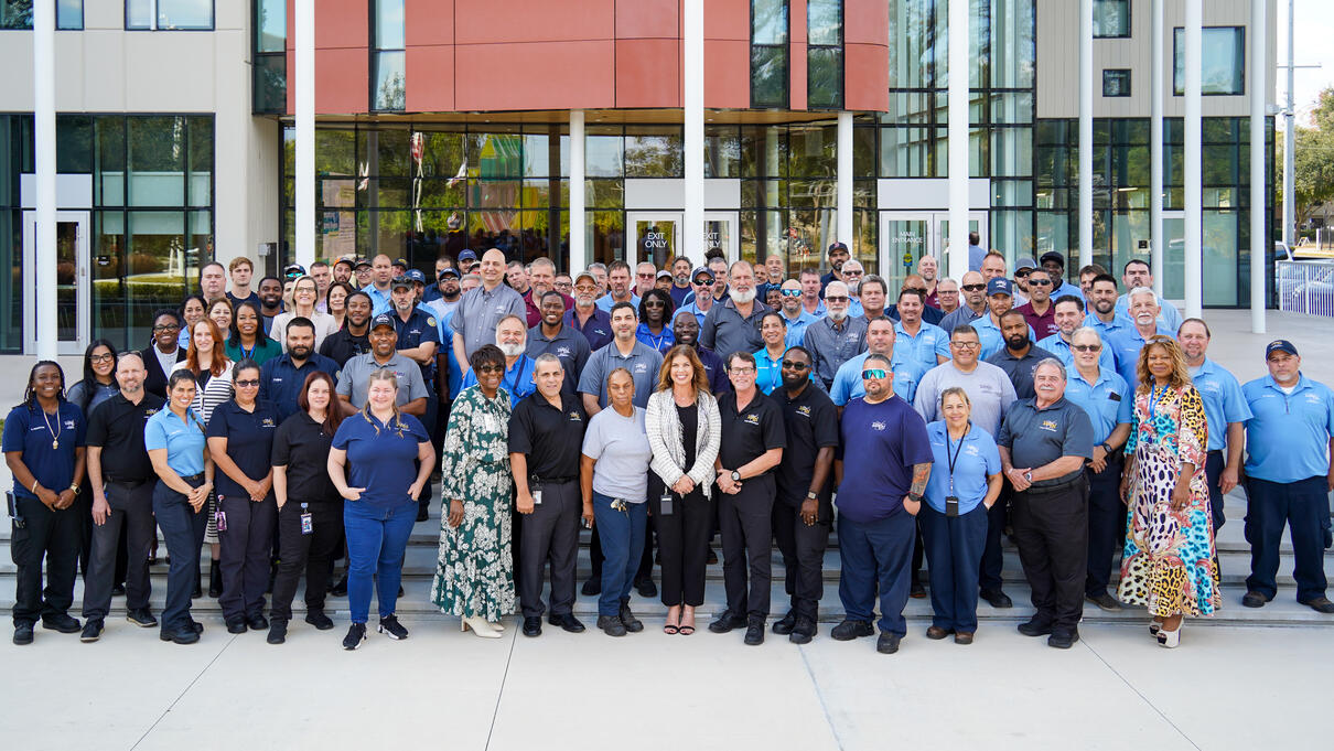 Group photo of many people standing outside a modern building.