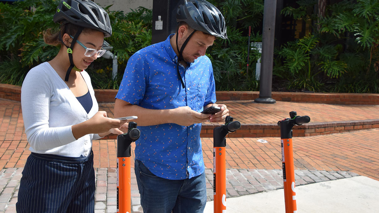 2 scooter riders using their mobile devices