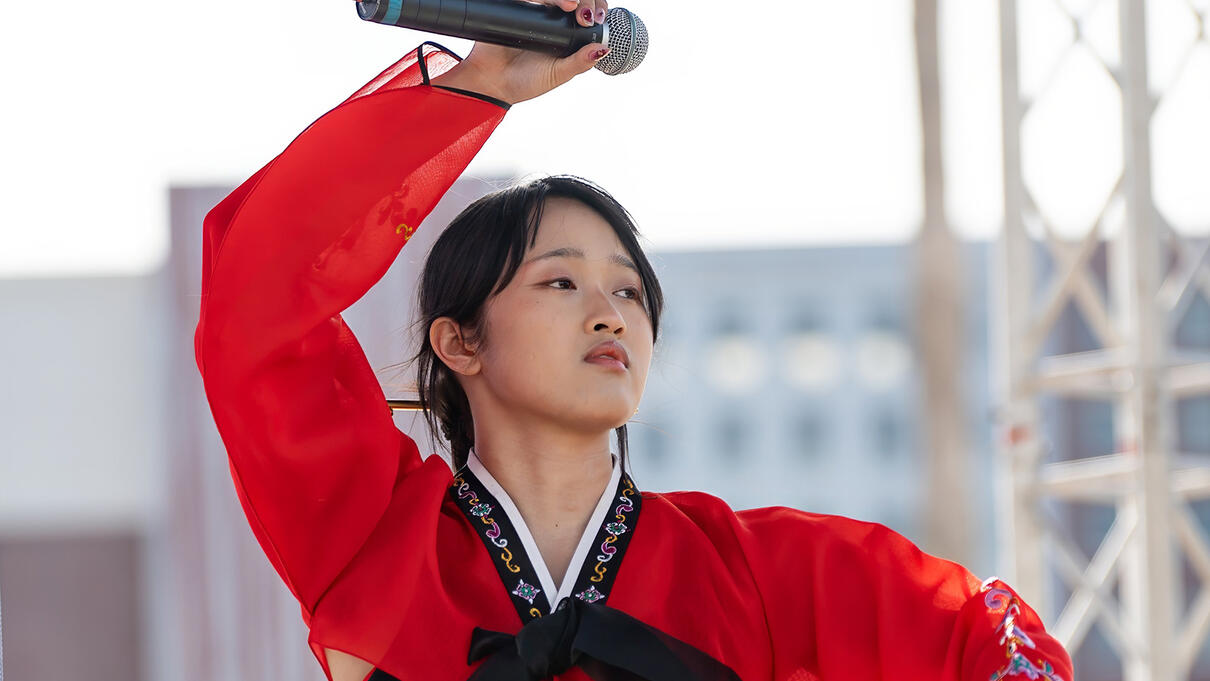 Performer in traditional attire with microphone at Tampa Asian Pacific event.