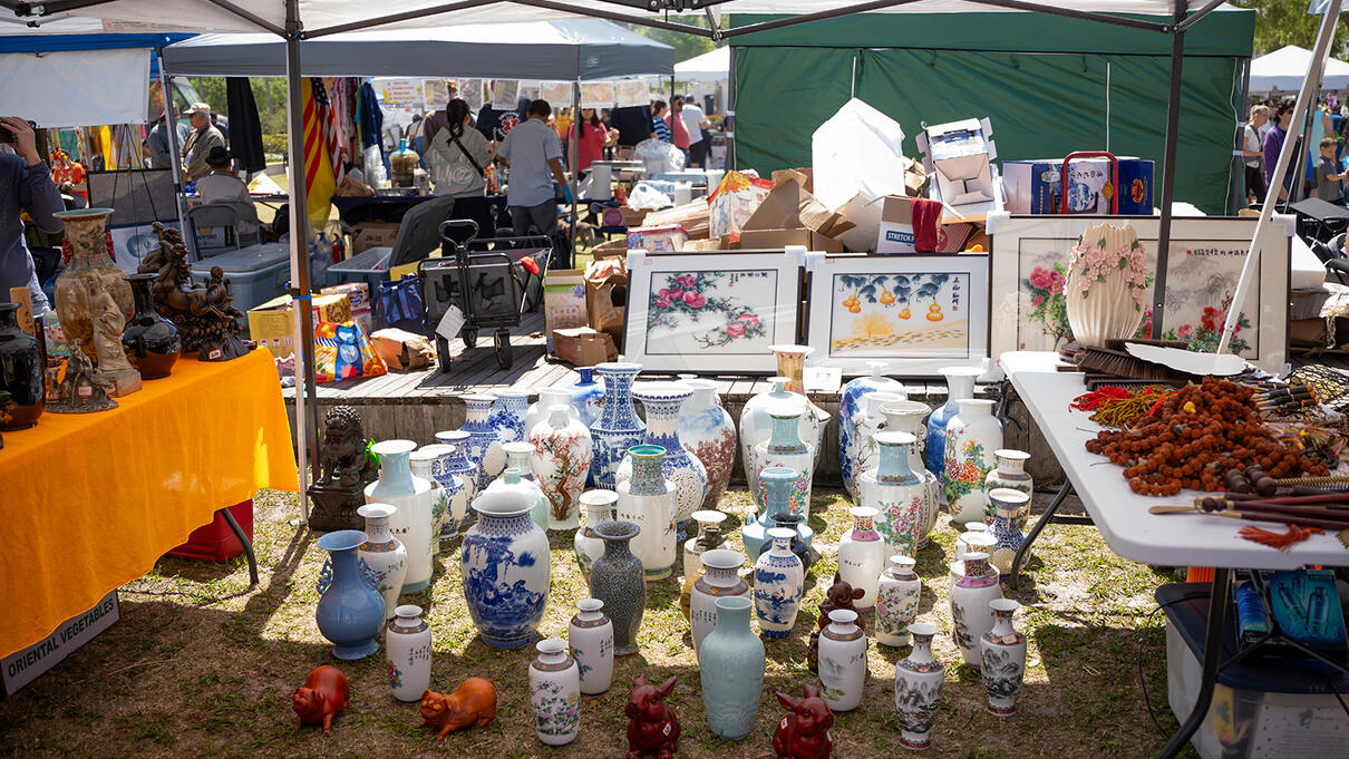 Outdoor market with various Asian-inspired ceramics and art under tents.