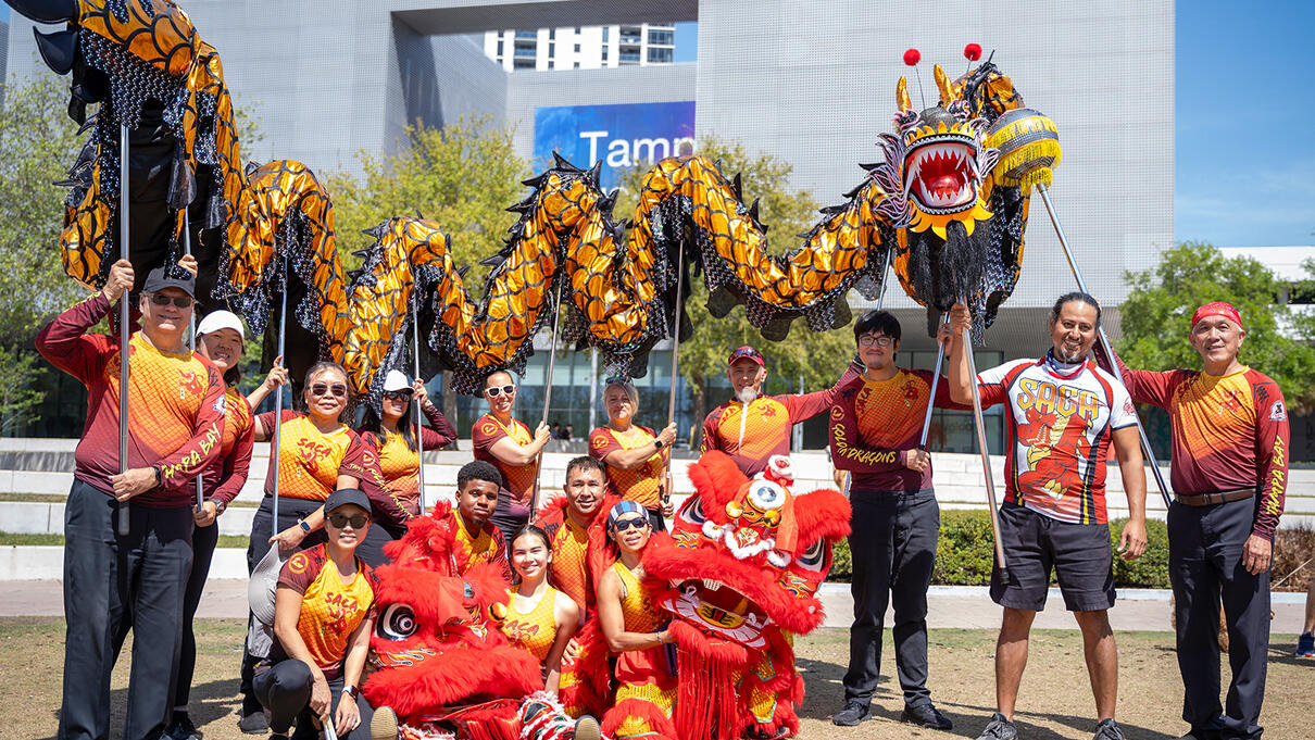 Dragon dance group in colorful attire, posing outdoors in Tampa.