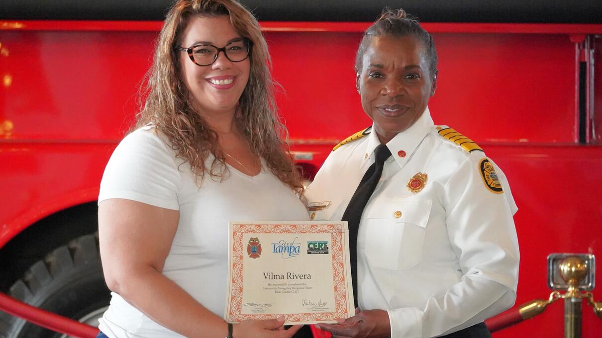Two women smiling, one in uniform, holding a Tampa CERT Spring graduation certificate.