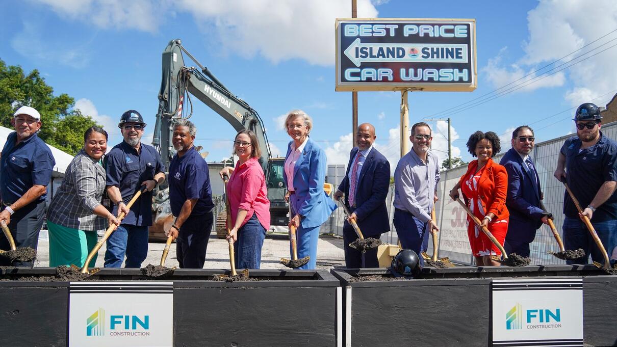 Group at urban REWORX groundbreaking, holding shovels in front of construction site.