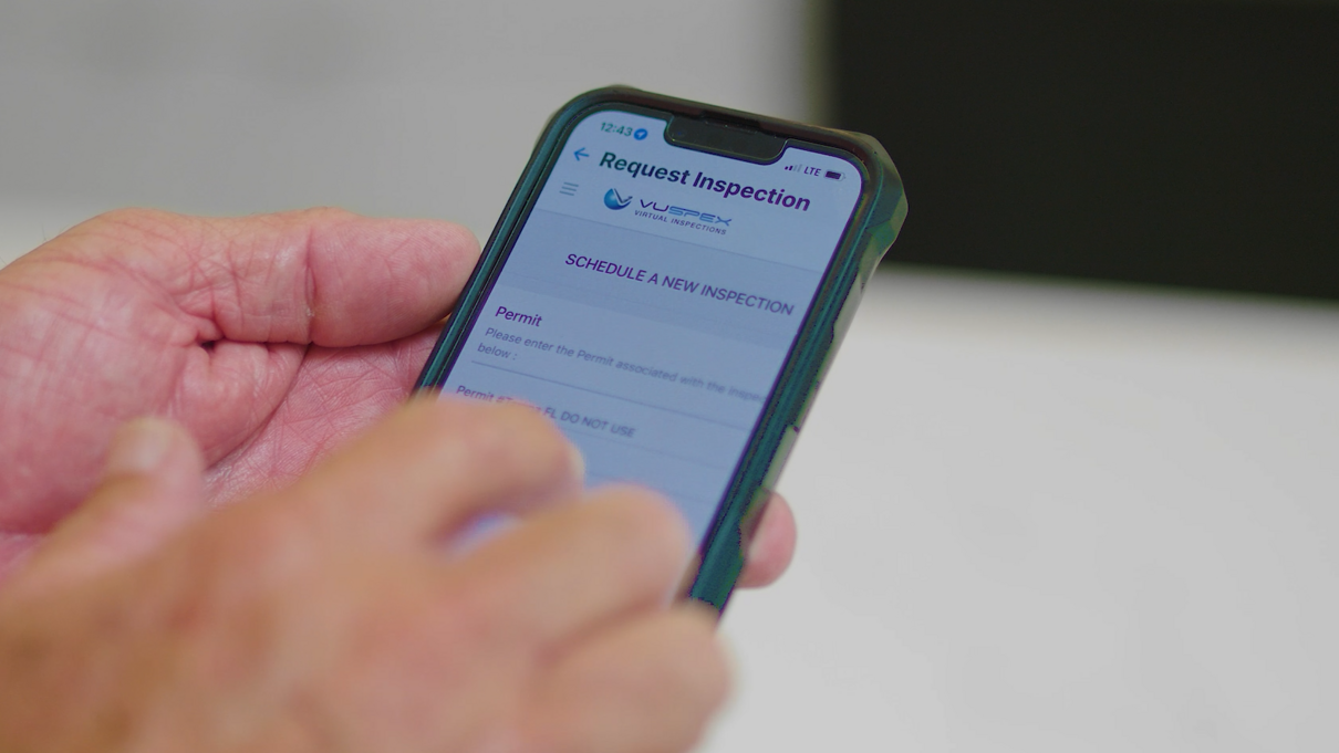 Hand holding a smartphone displaying a Vuspex application screen.